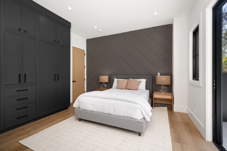 Modern bedroom with dark wardrobes and chevron accent wall.