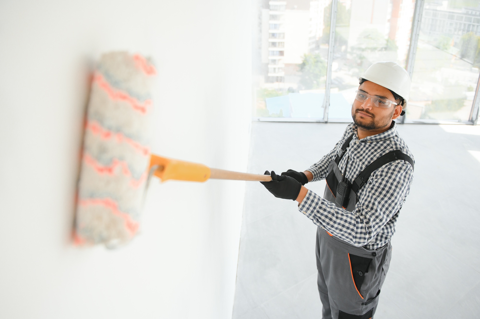 Indian Painter painting the office wall with roller paint